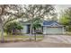 One-story house with a green exterior, two-car garage, and palm trees at 19329 Autumn Woods Ave, Tampa, FL 33647