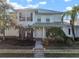Two-story light green house with a white door, landscaping, and a metal roof on a sunny day at 322 Ibisview Ln, Apollo Beach, FL 33572
