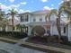 Two-story light green house with a white door, landscaping, and a metal roof on a sunny day at 322 Ibisview Ln, Apollo Beach, FL 33572