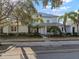 Two-story light green house with a white door, landscaping, and a metal roof on a sunny day at 322 Ibisview Ln, Apollo Beach, FL 33572