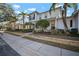 Two-story light green house with a white door, landscaping, and a metal roof on a sunny day at 322 Ibisview Ln, Apollo Beach, FL 33572