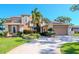 Two-story house with a tan facade, lush landscaping, and a circular driveway at 36 Freshwater Dr, Palm Harbor, FL 34684