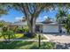 Single-story home with mature landscaping and a large tree in front at 690 Wild Oak Ln, Palm Harbor, FL 34683