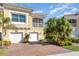 Front view of a two-story townhome with a two-car garage and lush landscaping at 4284 Expedition Way, Osprey, FL 34229