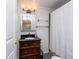 Clean bathroom with dark wood vanity, glass shelves, and shower/tub combo at 11008 Browning Rd, Lithia, FL 33547