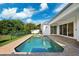 An in-ground backyard pool with brick pavers, next to a home with sliding glass doors at 34 Concord Dr, Dunedin, FL 34698