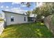 Large backyard with grassy area, screened patio, and white picket fence at 918 Windward Way, Palm Harbor, FL 34685