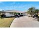 Front view of a single-story house with a large driveway and palm trees at 1906 Wolf Laurel Dr, Sun City Center, FL 33573