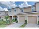 Tan two-story townhome with attached garage and landscaped front yard at 7064 Towne Lake Rd, Riverview, FL 33578