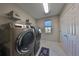 Bright laundry room features modern washer and dryer, ample shelving, and tile flooring at 12609 Pensacola Ct, Riverview, FL 33579