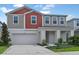 Two-story home with gray and red siding, white garage door, and landscaping at 12986 Wellspring Dr, Lithia, FL 33547