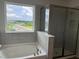 Primary bathroom featuring a soaking tub, glass enclosed shower, and large window with a scenic view at 16033 7Th E Ave, Bradenton, FL 34212