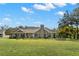 Lush backyard view of a gray house with blue skies and a large green yard at 13213 106Th Ave, Largo, FL 33774