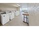 Clean and functional laundry room equipped with multiple washing machines and a folding table at 5915 Sea Ranch Dr # 408, Hudson, FL 34667