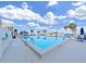 Exterior of swimming pool area on a sunny day with blue skies and white clouds, featuring lounge chairs and palm trees at 5915 Sea Ranch Dr # 408, Hudson, FL 34667