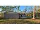 Exterior rear view of the home features a small patio area and an expansive grassy yard at 6906 Quail Hollow Blvd, Wesley Chapel, FL 33544