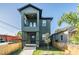 Two-story modern green house with a black roof, a small front yard, and a wooden fence at 1910 W Union St, Tampa, FL 33607