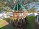 Wooden playset with slide, swings, and climbing features in a fenced backyard at 12352 Monarch Cir, Seminole, FL 33772