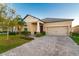 Tan house with brown door, paved driveway, and landscaped yard at 13423 White Sapphire Rd, Riverview, FL 33579