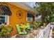 Small patio with orange house, black awnings, lime green chairs, and potted plants at 1600 Beach Trl, Indian Rocks Beach, FL 33785