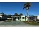 Quaint light green manufactured home with a covered patio and mature palm tree at 35127 Danny Dr, Zephyrhills, FL 33541