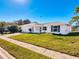 White single story house with attached garage and landscaped lawn at 8015 Idlebriar Ln, Port Richey, FL 34668