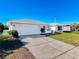 A white single-story house with attached garage and a well-maintained lawn at 8015 Idlebriar Ln, Port Richey, FL 34668