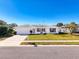 White single story house with a neatly landscaped lawn and driveway at 8015 Idlebriar Ln, Port Richey, FL 34668