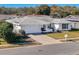 White single-story house with a gray roof, driveway, and well-maintained lawn at 8015 Idlebriar Ln, Port Richey, FL 34668