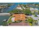 Aerial view of terracotta-roofed house situated on waterfront property, showcasing mature trees and a private dock at 1997 Kansas Ne Ave, St Petersburg, FL 33703