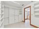 Bright walk-in closet with custom storage solutions, including shelves, drawers, and hanging rods, leading to bathroom at 1997 Kansas Ne Ave, St Petersburg, FL 33703