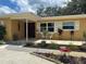 Inviting front entrance with a tiled porch, white chairs, and decorative flower planters, adding charm and curb appeal at 209 Westwinds Dr, Palm Harbor, FL 34683