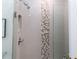 Shower with pebble tile accent wall and glass door at 209 Westwinds Dr, Palm Harbor, FL 34683