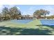 Two well-maintained tennis courts with clubhouse in background at 5912 Willow Creek Ct, New Port Richey, FL 34655