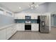 Modern kitchen with white cabinets, stainless steel appliances, and teal backsplash at 7108 Riverwood Blvd, Tampa, FL 33615