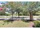 Landscaped yard with a white fence and mature trees at 8751 Falling Blue Pl, Riverview, FL 33578