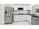 Clean kitchen space with stainless steel appliances, white cabinets, and black countertops on white tile floor at 1847 Shore S Dr # 509, South Pasadena, FL 33707