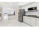 Open concept kitchen featuring stainless steel appliances, white cabinets, and black countertops on white tile floor at 1847 Shore S Dr # 509, South Pasadena, FL 33707