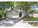Charming home with a two-car garage and neatly manicured front yard, highlighted by mature trees and shrubbery at 14324 Moon Flower Dr, Tampa, FL 33626
