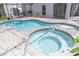 Aerial shot of refreshing pool and spa featuring tiled trim, brick patio, and backyard entertaining area at 14324 Moon Flower Dr, Tampa, FL 33626