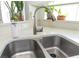 Double stainless steel sink with modern faucet and bright natural light from the window at 14324 Moon Flower Dr, Tampa, FL 33626