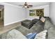 Bright living room featuring a comfortable sectional couch, a ceiling fan, and views of the landscaped yard at 2640 Westchester N Dr, Clearwater, FL 33761