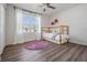 Cozy bedroom with wood-look floors, a window with white curtains, and a wood frame bed at 35608 Welby Ct, Zephyrhills, FL 33541