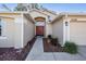 Inviting front entrance with a red double door, manicured landscaping, and attached garage at 35608 Welby Ct, Zephyrhills, FL 33541