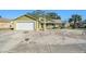 House exterior featuring a green color, white garage door, and a sandy front yard at 8150 Rose Petal Ct # E, Port Richey, FL 34668