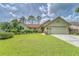 Single-story house with a light green exterior, attached garage, and well-maintained lawn at 9719 Pleasant Run Way, Tampa, FL 33647