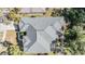 An aerial view of a well maintained roof and backyard featuring beautiful greenery and a covered patio at 12306 Woodlands Cir, Dade City, FL 33525