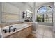 Elegant bathroom featuring a soaking tub, tile surround, and bright natural light at 12306 Woodlands Cir, Dade City, FL 33525