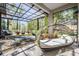 Relaxing sunroom with a modern lounger, fire pit, and views of the lush surroundings at 12306 Woodlands Cir, Dade City, FL 33525