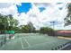 View of tennis courts surrounded by lush greenery and secure fencing for recreation at 12306 Woodlands Cir, Dade City, FL 33525